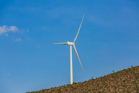Wind farm. Among farms and hills, wind turbines emerge as a symbol of clean energy, converting the kinetic energy of the wind into electricity.の写真素材