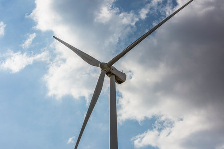 Wind farm. Among farms and hills, wind turbines emerge as a symbol of clean energy, converting the kinetic energy of the wind into electricity.の写真素材