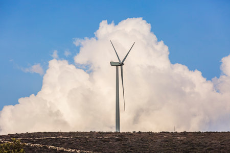 Wind farm. Among farms and hills, wind turbines emerge as a symbol of clean energy, converting the kinetic energy of the wind into electricity.の写真素材