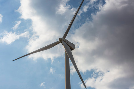Wind farm. Among farms and hills, wind turbines emerge as a symbol of clean energy, converting the kinetic energy of the wind into electricity.の写真素材