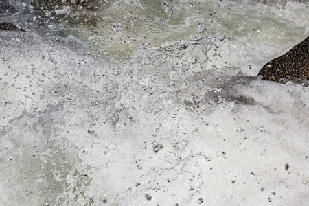 Moving river water. The powerful crash of a river rushing forcefully between rocks. White, foamy waves splash in all directions.の写真素材