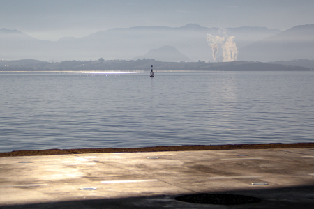 Looking from the dock of the bay toward the mountains, the bouy and the smokeの写真素材