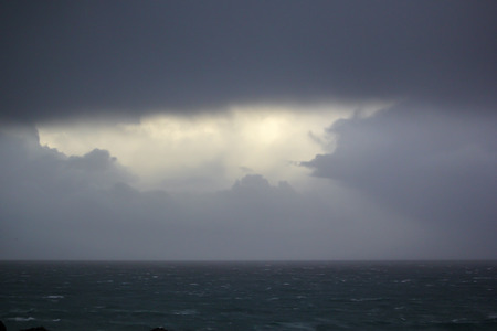 Opening in the clouds at rough seaの写真素材