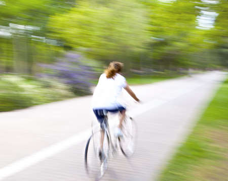 Riding bike on morning light through the parkの写真素材
