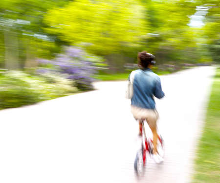 Riding bike on morning light through the parkの写真素材