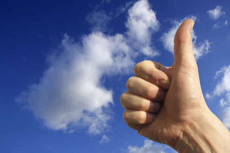 a hand saying ok against a blu skyの写真素材