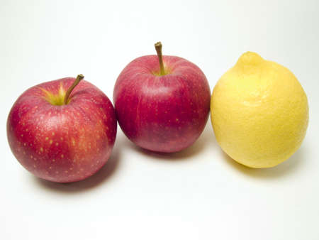 Two red apples and a yellow lemon in a white backgroundの写真素材