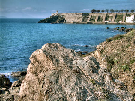 Sea landscape with green sea, rocks and lighthouse on the coastの写真素材