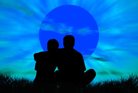 Lovers on the grass in front of the sunsetの写真素材