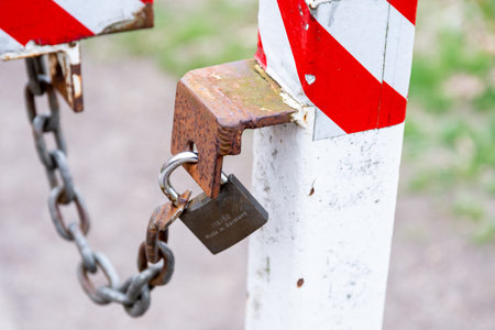 Berlin, Berlin/Germany - 24.03.2019: A padlock attached to a chain and a pole to secure a red-white...
