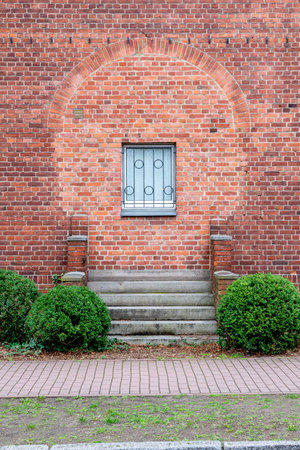Berlin, Berlin/Germany - 24.03.2019: A red brick wall with a window, where before a door was bricked up. The stairs and the brick railing are still present and I see another brick color at the place.のeditorial素材