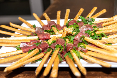 Berlin, Berlin/Germany - 03.11.2018: A plate with finger food, consisting of pastry sticks wrapped in salad and ham and arranged in a star shape.のeditorial素材