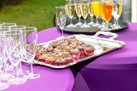 Berlin, Berlin/Germany - 03.11.2018: Champagne reception with empty and full glasses, filled with sparkling wine and juice and a tray with small pastries or cupcakes.のeditorial素材