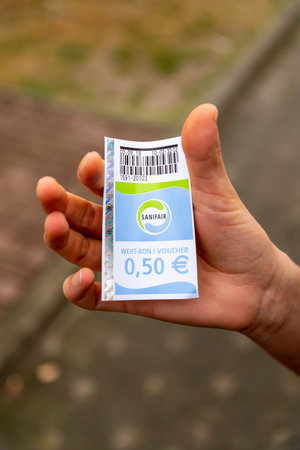Berlin, Berlin/Germany - 03.09.2019: A ticket or voucher in hand from the company Sanifair, a toilet payment system at motorway service areas in Germany with a printed price of fifty cents.のeditorial素材