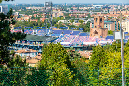 Bologna, Emilia-Romagna / Italy - 08/19/2020: The Stadio Renato Dall'Ara photographed from above through trees with the floodlights and view of the city in the background.のeditorial素材