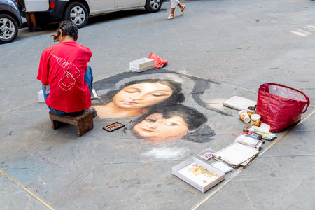Florence, Toscana / Italy - 08/24/2020: A street painter painting a picture on the sidewalk showing a woman and a childのeditorial素材