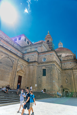 The cathedral of Florence with tourists in the foreground at one corner photographed from below against the sun.のeditorial素材