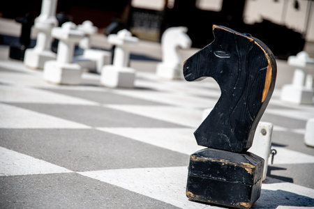 A Black Knight Chess Piece with a Horse Head on a Grand Gray-White Chessboard, with Other Pieces in...