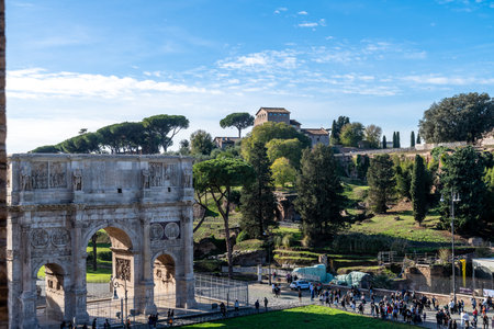Roma, Lazio - Italy - 11-23-2022: Tourists at Arch of Constantine, a triumphal arch with figures and battle scenes. San Sebastiano church on Palatine Hill in the backdrop.のeditorial素材