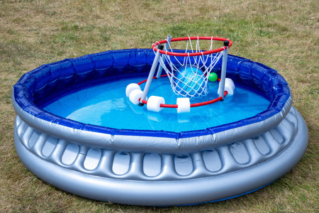 An inflatable pool with a mini basketball hoop stands ready for a game on a quiet summer day