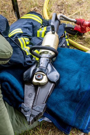 Close-up view of a firefighter's hydraulic rescue tool, crucial for extrication, alongside protective gearの写真素材