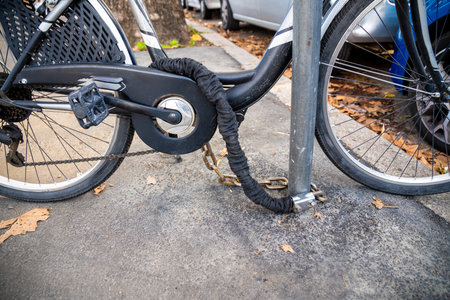 A bike locked to a post with a chain, showing a common urban method for theft preventionの写真素材