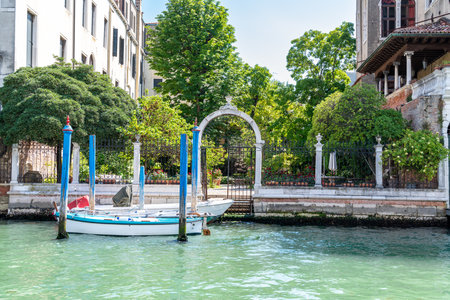 Venice, Veneto - Italy - 06-10-2021: A tranquil spot with a boat, mooring poles, and arch by the canalのeditorial素材