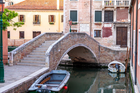 Venice, Veneto - Italy - 06-10-2021: Time-worn brick bridge arching over a quiet Venetian canalのeditorial素材