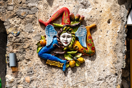 Colorful ceramic Trinacria sculpture on stone wallの写真素材