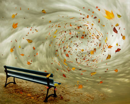 park bench with autumn leaves flying in a whirlwindの写真素材