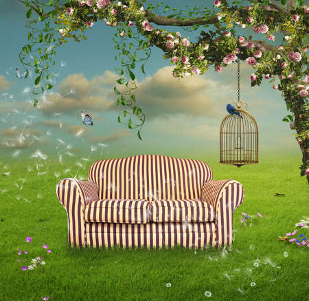 Flowered tree with roses and ivy in a field with a sofa and a cageの写真素材