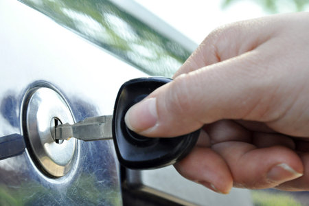 a hand puts a key in the lock of a car
