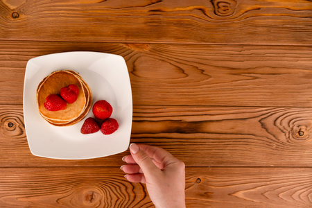 Pancakes with berries on a white plate on the table.の写真素材