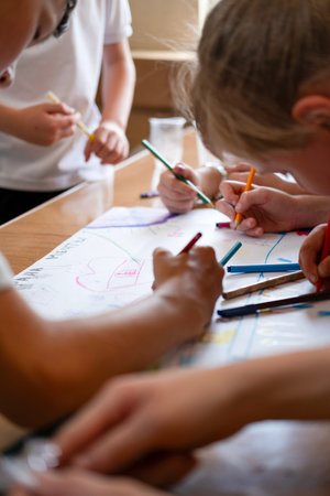 Children draw on the poster with pencils and paints.