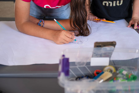 Children draw on the poster with pencils and paints.
