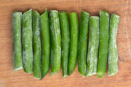 Frozen sticks of asparagus on wood background. Vertical view. Eleven sticksの写真素材