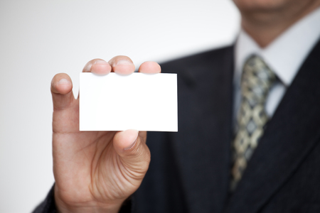 Businessman showing his business card. Shallow depth of field - focus on fingers and card. You can just add your text there.の写真素材