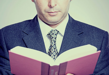 Businessman or teacher holding and reading from a book
