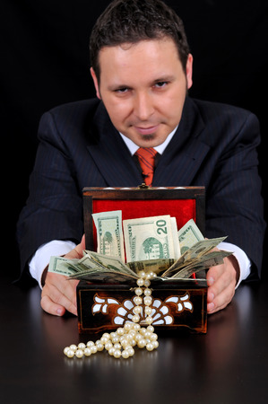 Businessman is extending gift box. Maybe bribing on the black backgroundの写真素材