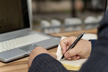 man's hand writes with a pen in a notebook.の写真素材