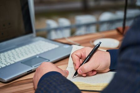 close-up male hand writes in notebook writing on notebook backgroundの写真素材