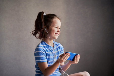 beautiful funny girl listening to music on a smartphone with headphones