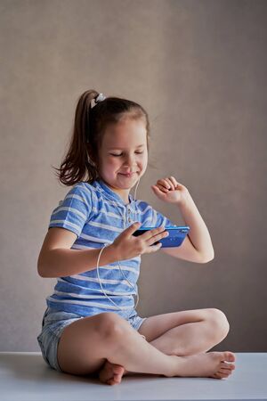 beautiful funny girl listening to music on a smartphone with headphonesの写真素材
