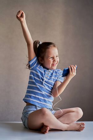 beautiful funny girl listening to music on a smartphone with headphonesの写真素材