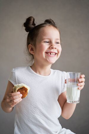 funny child with a glass of milk and bread on a gray background. real milk from the village.の写真素材