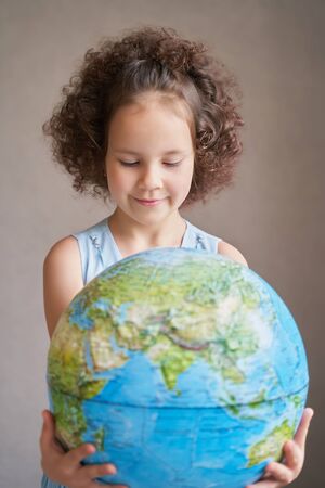children's day. a beautiful curly-haired girl holds the planetの写真素材