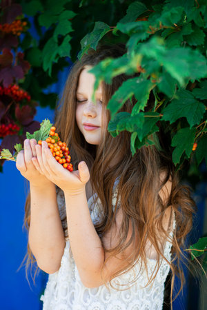 beautiful wonderful girl in a white dress in a Rowan tree.