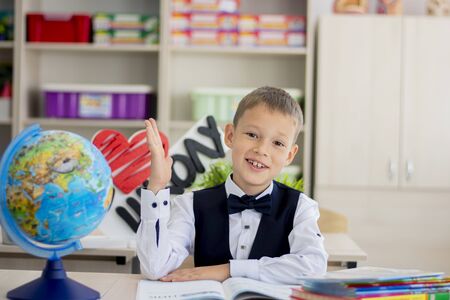 a schoolboy at school sits in class and stretches his hand.の写真素材