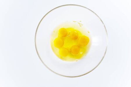 bright broken eggs in a glass plate on a white table.の写真素材