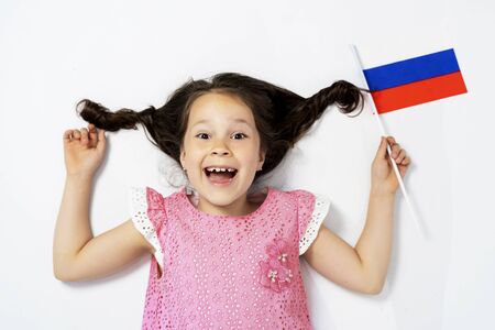 a beautiful girl lies on a white background next to the flag of Russia. the view from the topの写真素材